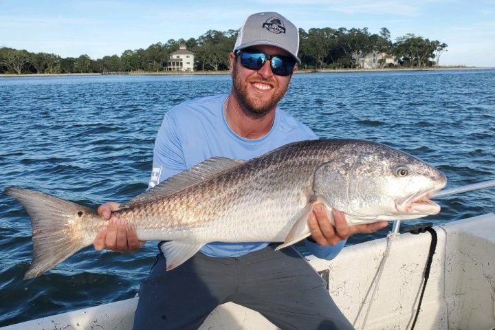 a man holding a fish on a boat in a body of water