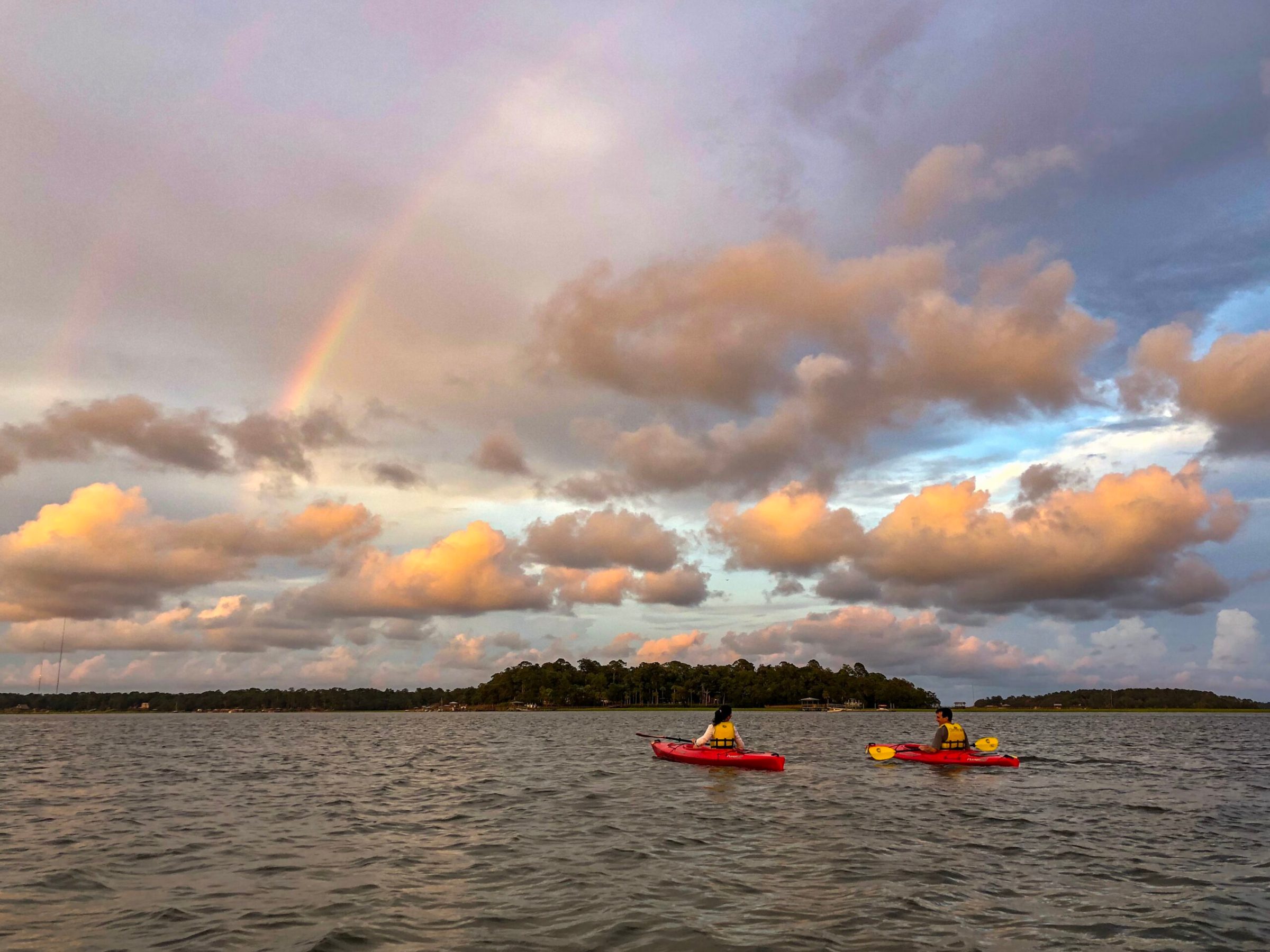 kayaking under rainbow 2 a small boat in a large body of water